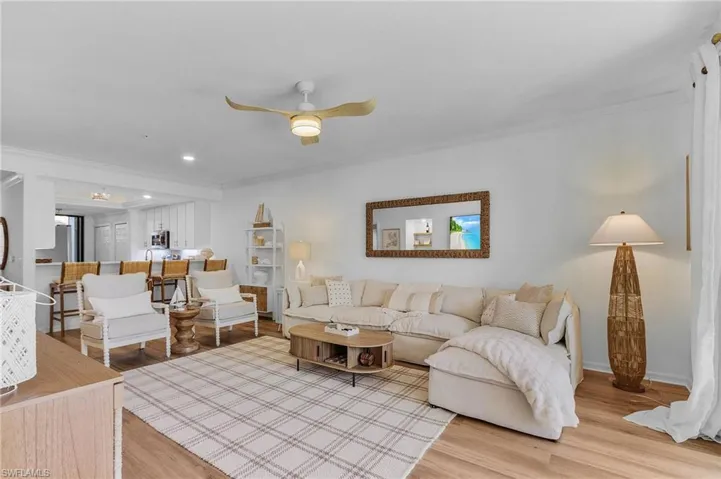 Living room with hardwood / wood-style floors, ceiling fan, and ornamental molding