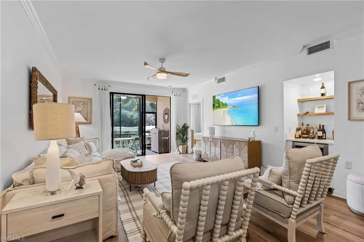 Living room featuring light hardwood / wood-style flooring, ceiling fan, and bar area.