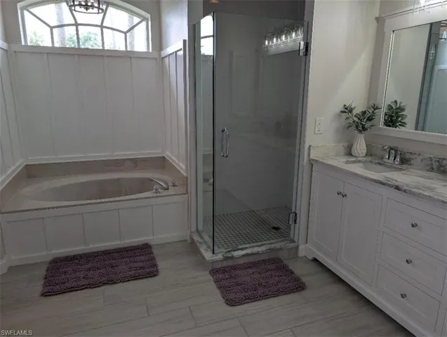 Full bathroom featuring a bath, a shower stall, and vanity