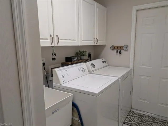 Laundry area featuring independent washer and dryer and cabinet space