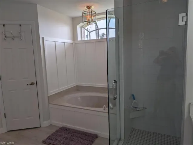 Bathroom featuring a shower stall, a garden tub, and wood finished floors