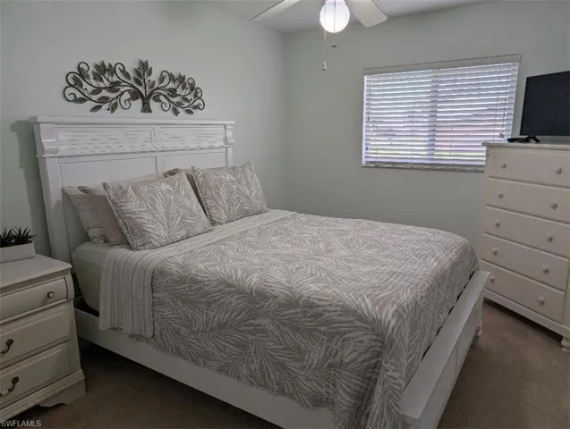 Carpeted bedroom with a ceiling fan