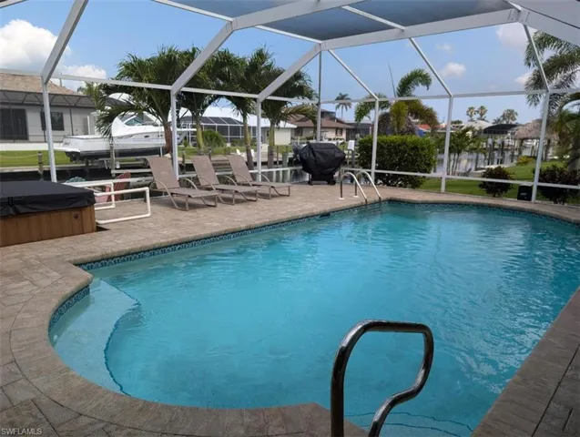 Outdoor pool with a hot tub, a patio area, a lanai, and a residential view