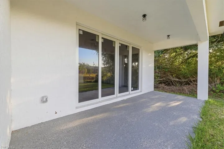 Covered patio featuring a smooth concrete floor, white stucco exterior, and large sliding glass doors