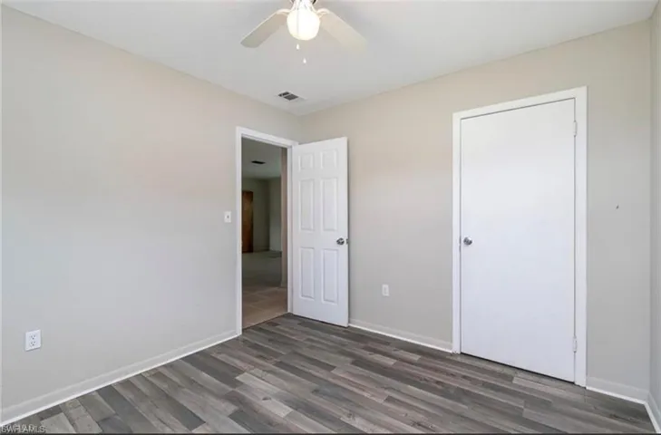 Unfurnished bedroom with dark wood-style flooring and ceiling fan