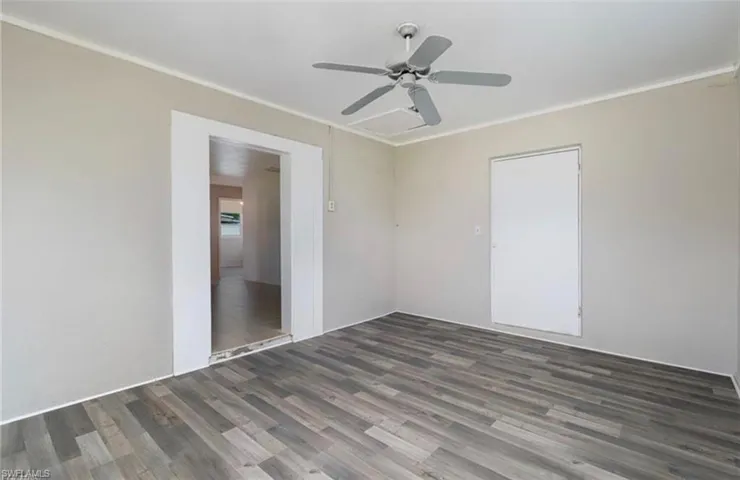 Spare room featuring dark wood-type flooring, crown molding, and ceiling fan