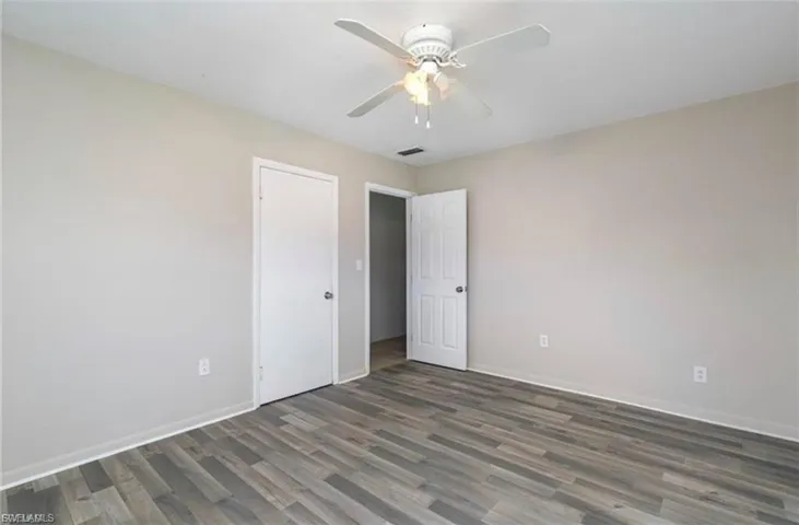 Unfurnished bedroom with ceiling fan and dark wood finished floors