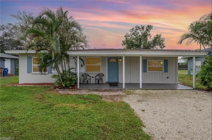 Single story home with a front lawn, a porch, driveway, and board and batten siding