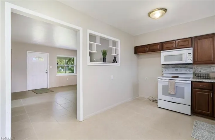Kitchen with white appliances, dark brown cabinetry, and decorative backsplash
