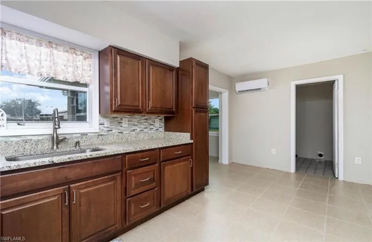 Kitchen featuring light stone counters, decorative backsplash, and a wall mounted AC