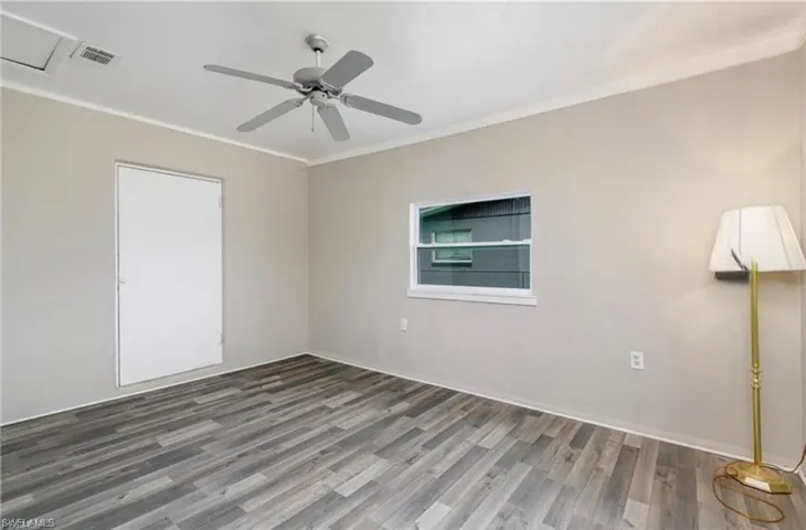 Empty room featuring wood finished floors, a ceiling fan, and ornamental molding