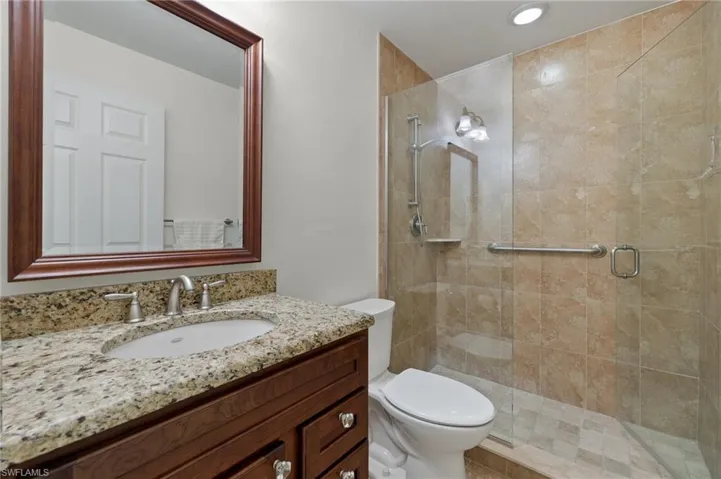 Updated hall bath with tiled walk-in shower with frameless glass, new granite high-top vanity with new faucet & lighting fixtures.
