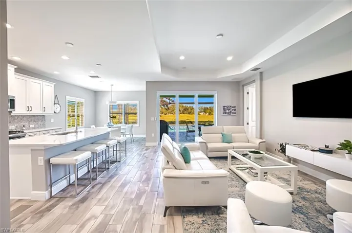 Living area with wood tiled floors, a raised ceiling, and recessed lighting