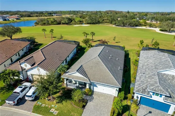 Aerial perspective of suburban area featuring a golf course and a nearby body of water