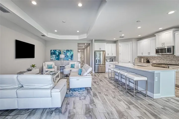 Living area featuring light wood-style flooring, recessed lighting, and a tray ceiling