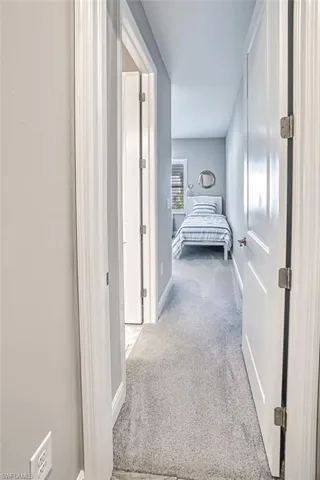 Hallway with light carpet and baseboards