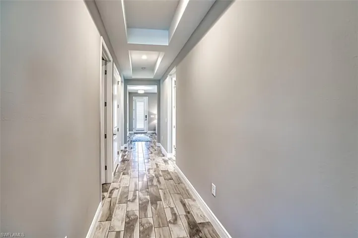 Corridor featuring wood finish floors and a tray ceiling