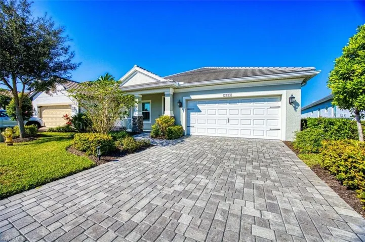 View of front facade with decorative driveway, covered porch, a garage, a tiled roof, and stucco siding