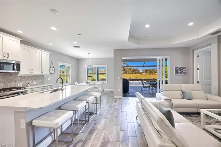 Kitchen with open floor plan, wood tiled floors, white cabinets, a breakfast bar, and a raised ceiling