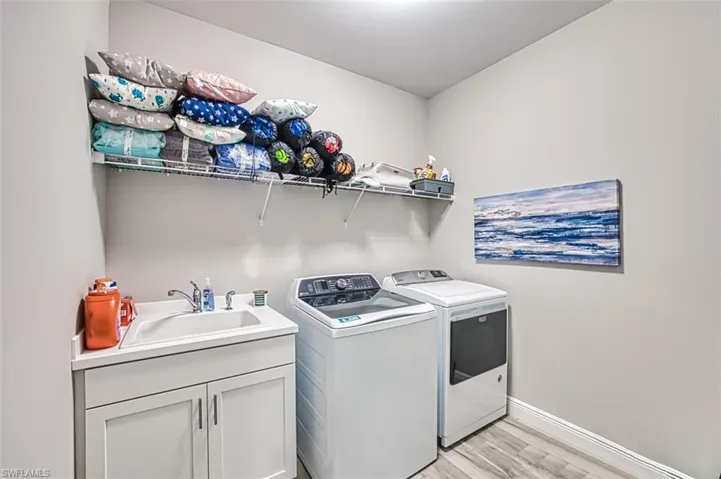 Laundry room with light wood finished floors, independent washer and dryer, and cabinet space