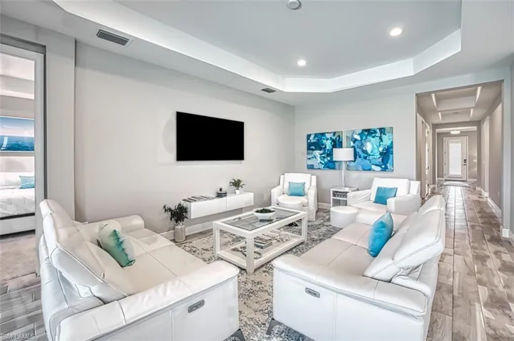 Living area with wood finish floors, a tray ceiling, and recessed lighting