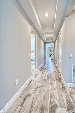 Hall featuring wood tiled floors, a raised ceiling, and recessed lighting