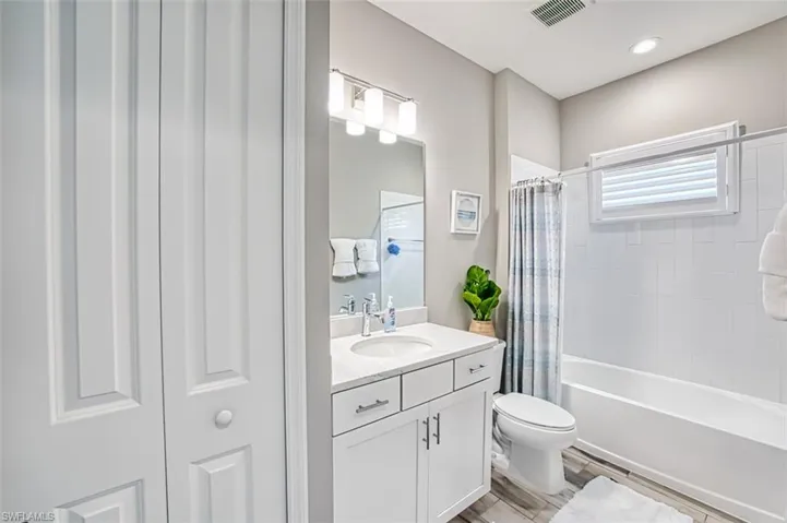 Bathroom featuring vanity, shower / bath combo with shower curtain, a closet, and wood finish floors