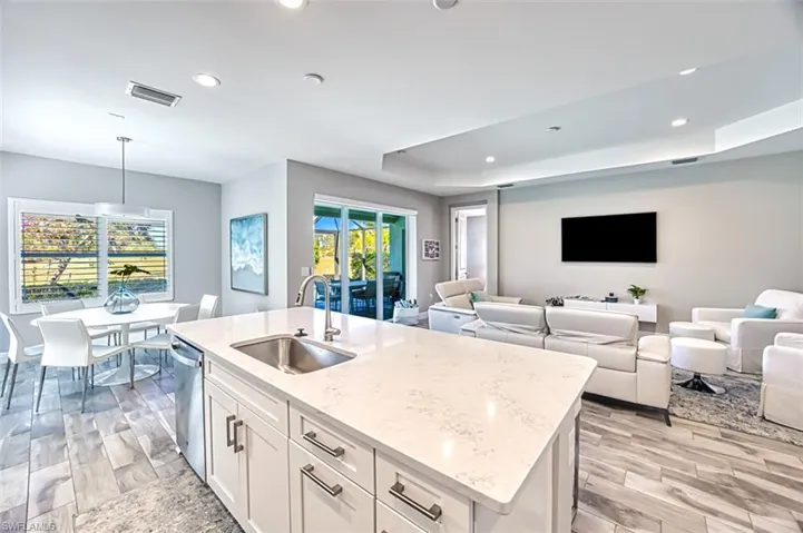 Kitchen with pendant lighting, white cabinets, wood tiled floors, light stone countertops, and a tray ceiling
