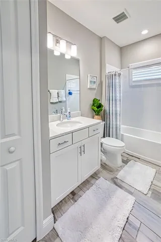 Full bath with vanity, shower / bath combination with curtain, and wood tiled floors