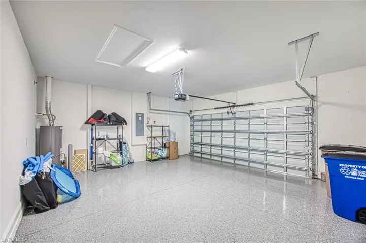 Garage with electric panel, gas water heater, and a garage door opener