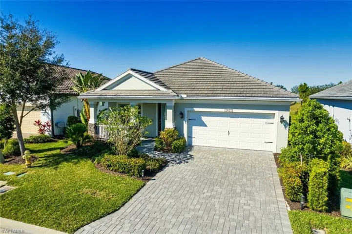 View of front of house featuring an attached garage, stucco siding, decorative driveway, a front yard, and covered porch