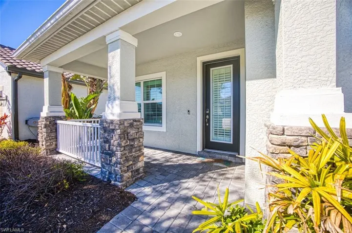 Doorway to property featuring covered porch and stucco siding