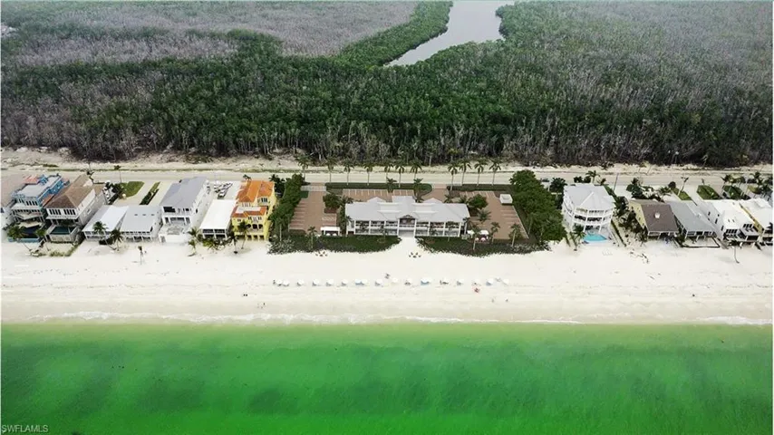 Beachfront property featuring a private white sand beach with turquoise waters, surrounded by mature trees