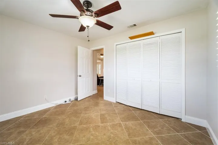 Unfurnished bedroom with a closet, ceiling fan, and tile patterned flooring