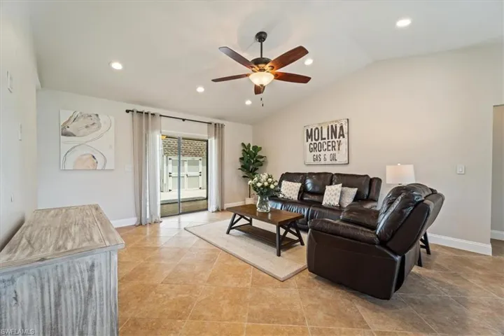 Tiled living room featuring vaulted ceiling and ceiling fan