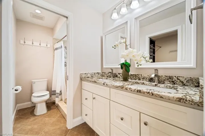 Bathroom with double vanity, tile patterned floors, and toilet