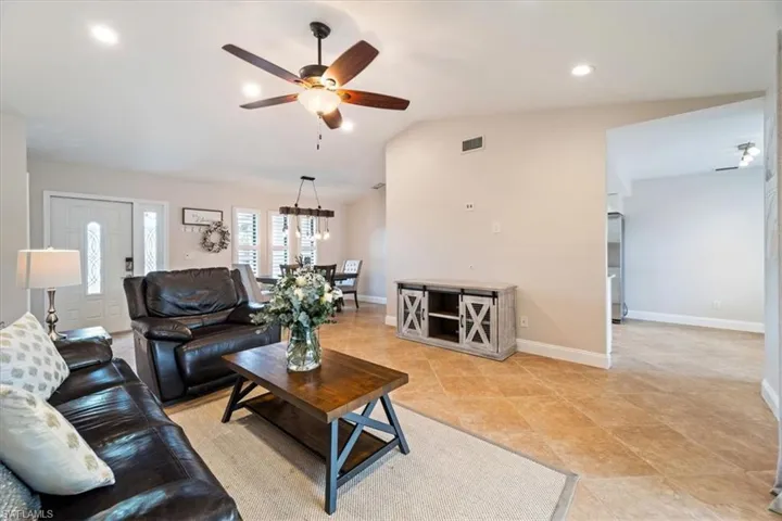 Living room with light tile patterned floors, lofted ceiling, and ceiling fan