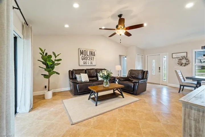 Living room featuring ceiling fan, vaulted ceiling, and light tile patterned floors