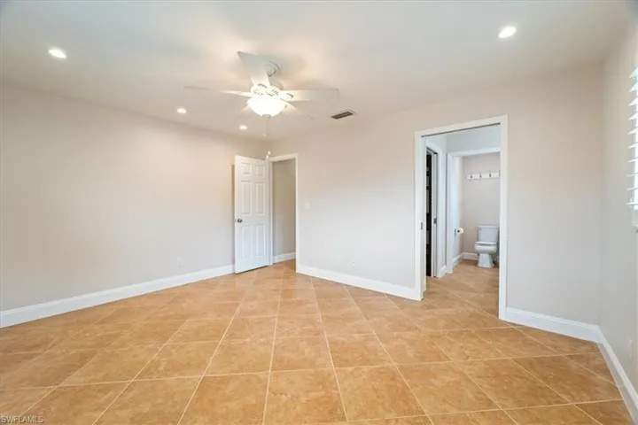 Unfurnished bedroom featuring ensuite bath, ceiling fan, and light tile patterned floors