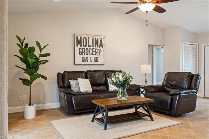 Tiled living room featuring ceiling fan and vaulted ceiling