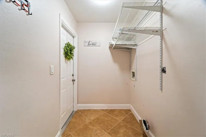 Laundry area with tile patterned flooring and hookup for a washing machine