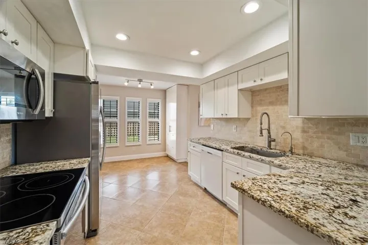 Kitchen with white cabinets, stainless steel appliances, backsplash, and sink