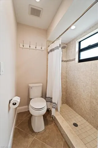 Bathroom featuring toilet, tile patterned flooring, and a shower with shower curtain