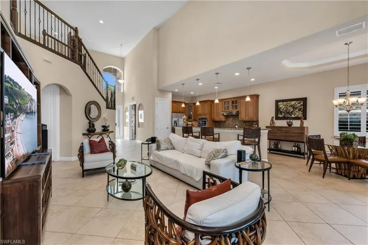 Living area with hanging lights, arched walkways, light tile patterned flooring, and healthy amount of natural light