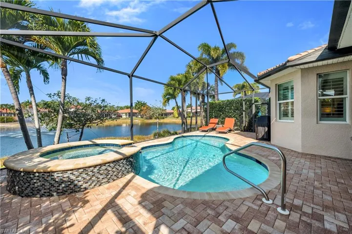 Relaxing pool / spa featuring a patio area, a sunroom, a water view, and glass enclosure