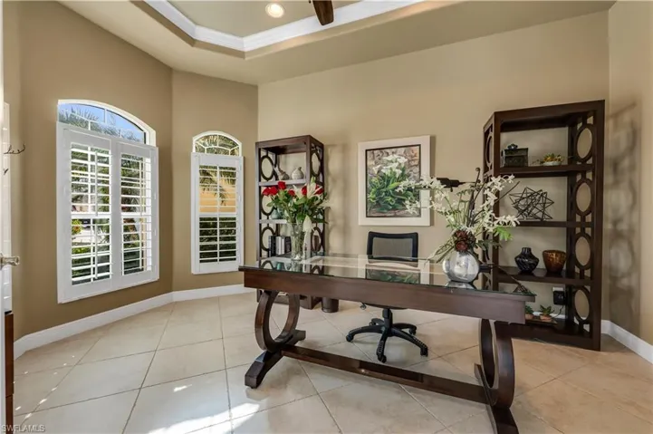 Office area featuring ornamental molding, a ceiling fan, light tile patterned flooring, and a raised ceiling