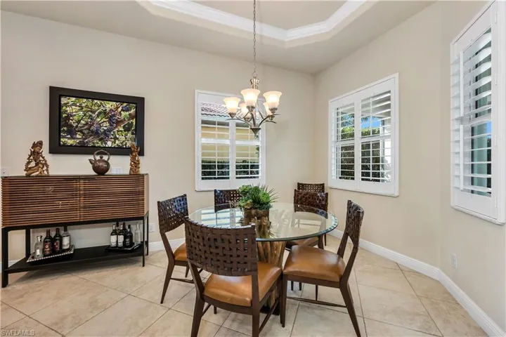 Dining area featuring a raised ceiling, a chandelier, crown molding, and light tile patterned floors