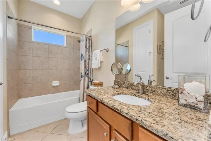 Full bath featuring vanity, light tile patterned floors, and shower / bathtub combination with curtain