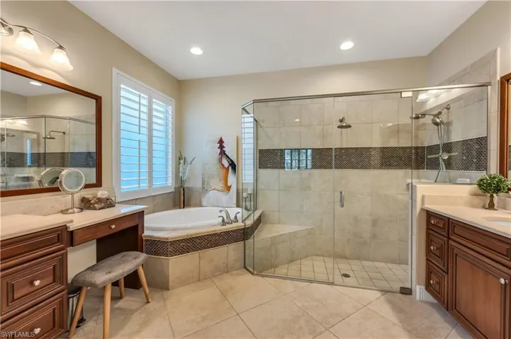 Full bath with vanity, a shower stall, a bath, and light tile patterned floors