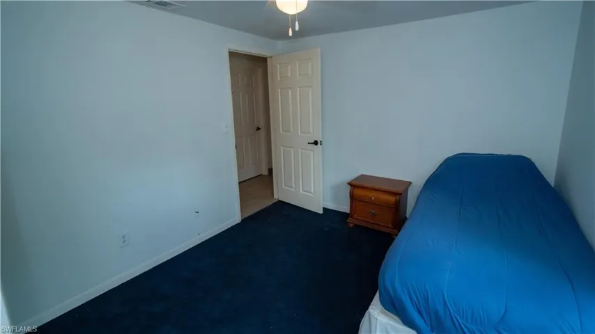 Unfurnished bedroom with dark colored carpet and ceiling fan